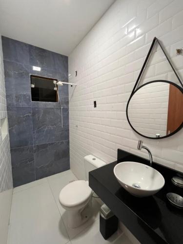 a bathroom with a sink and a toilet and a mirror at Casa em Dunas de Marapé -Jequia da praia in Jequia da Praia
