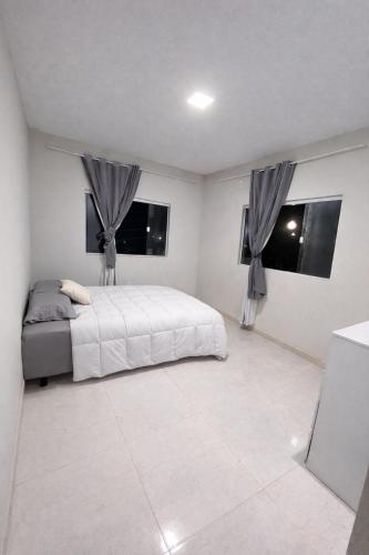 a white bedroom with a bed and two windows at Casa em Dunas de Marapé -Jequia da praia in Jequia da Praia