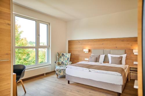a bedroom with a bed and a chair and a window at Buchners Hotel & Restaurant in Niederwinkling
