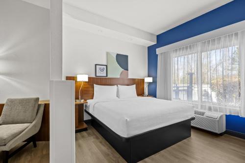 a bedroom with a bed and a chair and a window at Spark by Hilton Macon North in Macon