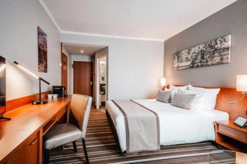 a hotel room with a bed and a desk at Leonardo Hotel Aachen in Aachen