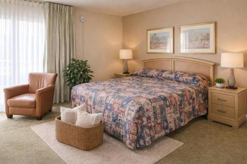 a hotel room with a bed and a chair at Queens Lodge Motel in West Palm Beach