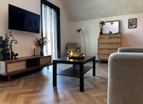 a living room with a coffee table and a tv at Luxe Vakantiehuis met privé Wellness in Zuidwolde