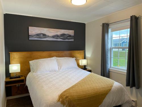 a bedroom with a bed with two lamps and a window at Buoy & Arrow Suites in Rocky Harbour