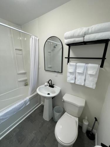 a white bathroom with a toilet and a sink at Buoy & Arrow Suites in Rocky Harbour