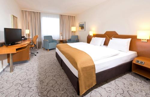 a hotel room with a bed and a desk and a television at Leonardo Hotel Heidelberg in Heidelberg