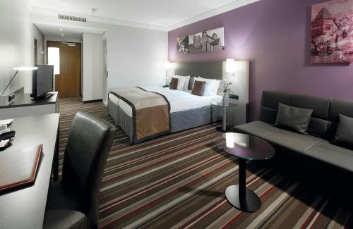 a hotel room with a bed and a couch at Leonardo Hotel Mönchengladbach in Mönchengladbach
