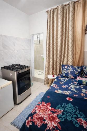 a living room with a bed and a stove at Kitnet Dream House 2 in Bayeux