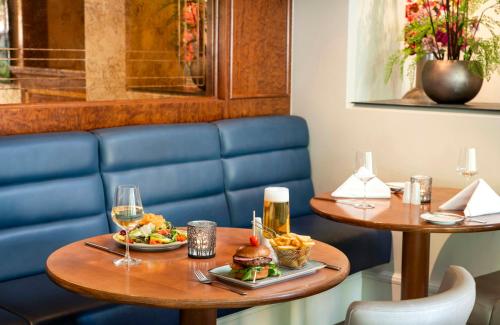 a restaurant with two tables with food and drinks at Leonardo Hotel Düsseldorf City Center in Düsseldorf