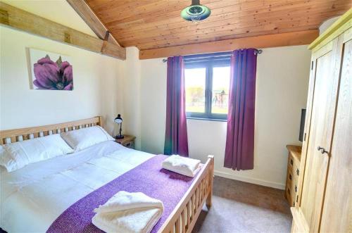 a bedroom with a bed and a window with purple curtains at 2 Bed in Llandinam oc-waa377 in Llandinam