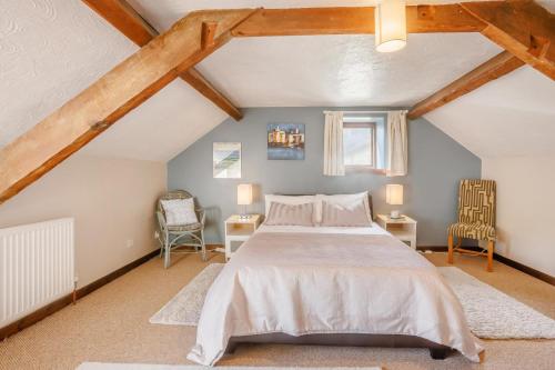 a bedroom with a bed and two chairs in a attic at 2 Bed in Swimbridge oc-n0208 in Swimbridge