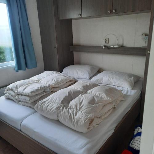 an unmade bed with white sheets and pillows at Zeeotter AanZee in Biggekerke