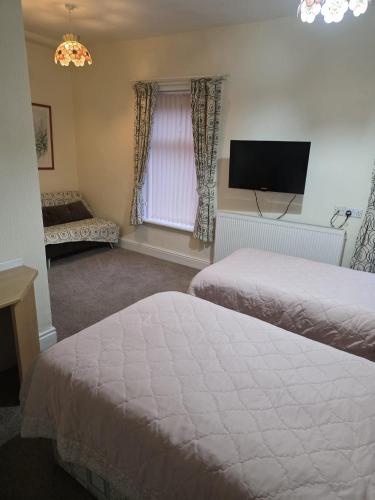 a bedroom with two beds and a flat screen tv at The Ormerod in Burnley