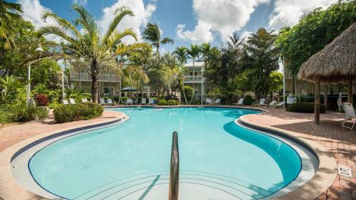 a swimming pool at a resort with a building in the background at Coral Villa by AvantStay Close 2 DT Key West Shared Pool Patio in Stock Island