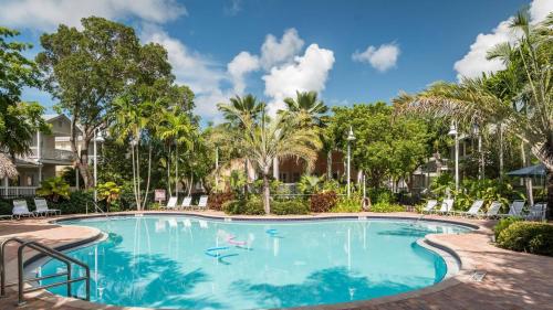a swimming pool at a resort with palm trees at Coral Villa by AvantStay Close 2 DT Key West Shared Pool Patio in Stock Island