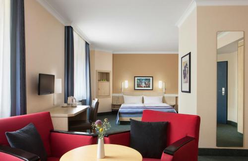 a hotel room with a bed and a table and chairs at Hotel Magdeburg City Center by Leonardo Hotels in Magdeburg
