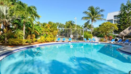 a large swimming pool with blue chairs and palm trees at Brisa Del Mar by AvantStay Communal Pool Gated Community Ocean Front in Key West
