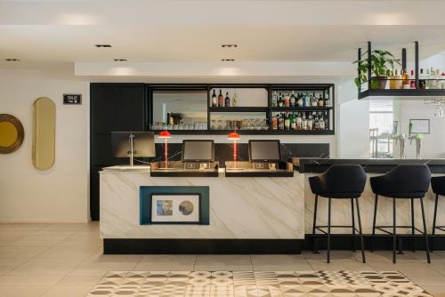 a bar with black stools in a room at Leonardo Hotel Rotterdam Savoy in Rotterdam