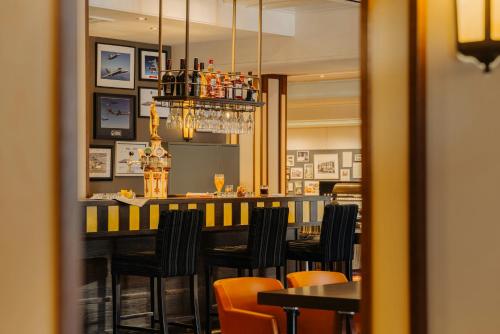 a dining room with a bar with black chairs at Leonardo Oranje Hotel Leeuwarden in Leeuwarden