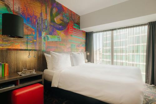 a bedroom with a white bed and a colorful wall at Leonardo Hotel Eindhoven City Center in Eindhoven