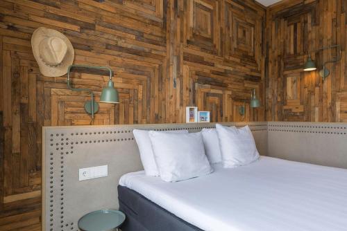 a bedroom with wooden walls and a bed with white pillows at Leonardo Hotel Vinkeveen Amsterdam in Vinkeveen