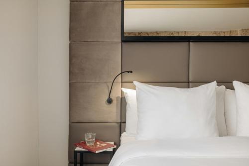 a bed with white pillows and a lamp on a table at Leonardo Boutique Hotel The Lancaster Amsterdam in Amsterdam