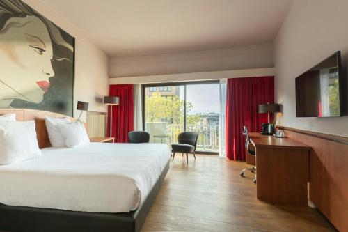 a hotel room with a bed and a desk and a window at Leonardo Hotel Utrecht City Center in Utrecht