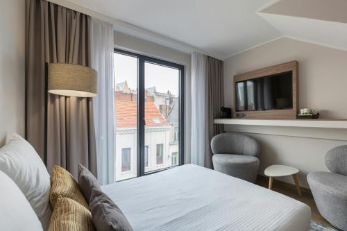 a hotel room with a bed and a window at Leonardo Hotel Antwerpen in Antwerp