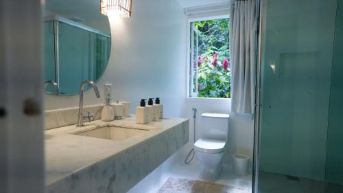 a bathroom with a sink and a toilet and a window at Fazenda Shanti in Alto Paraíso de Goiás