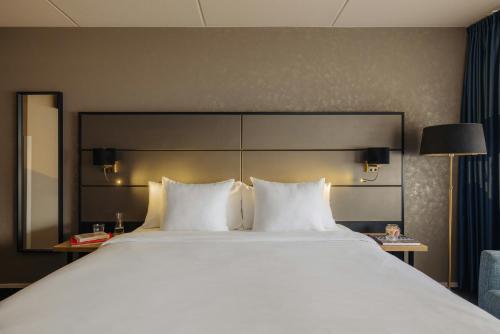a large bed with white pillows in a hotel room at Leonardo Hotel Groningen City Center in Groningen