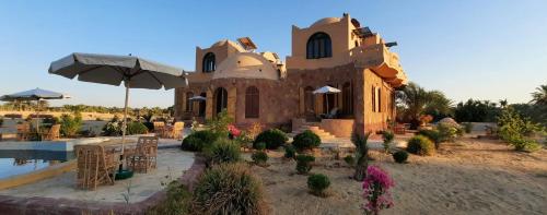 a building in the middle of a yard with plants at Siwa Salt Lake Lodge in Siwa