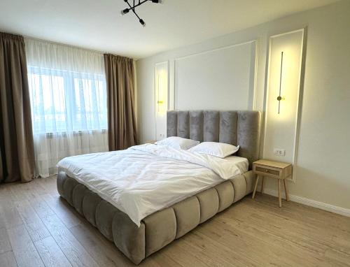 a bedroom with a large bed with a large window at Max Apartment in Ocna-Mureşului