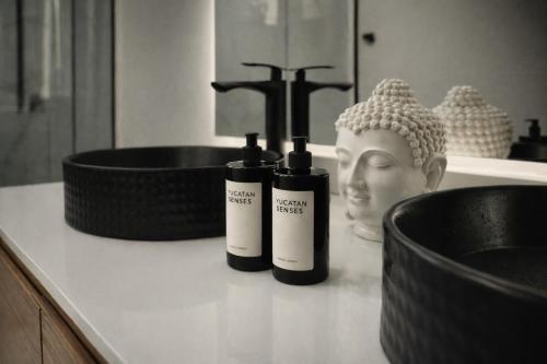 a bathroom counter with two bottles of soap and a statue at Nomad Luxe Tulum in Tulum