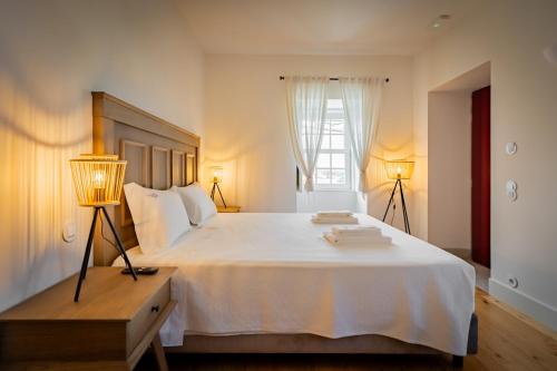 a bedroom with a large white bed with two lamps at Casa Da Brêa Viana do Castelo - Villa & Apartment in Viana do Castelo