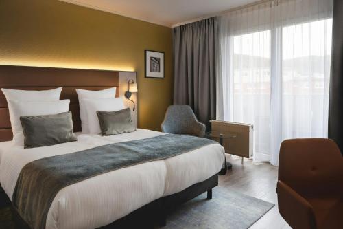 a hotel room with a large bed and a window at Leonardo Hotel Heidelberg City Center in Heidelberg