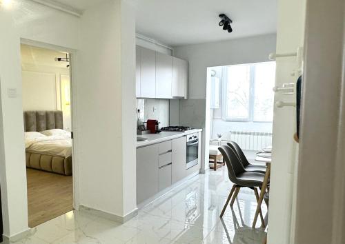 a kitchen with white cabinets and a bedroom with a bed at Max Apartment in Ocna-Mureşului