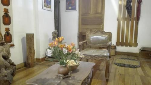 a living room with a table and a chair and flowers at Posada Junco y Capuli in Huancayo