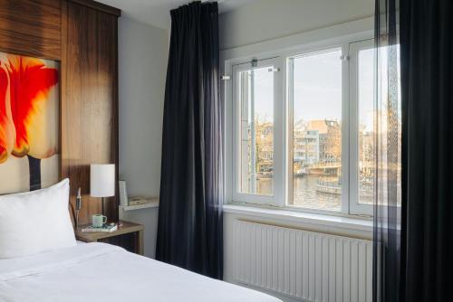 a hotel room with a bed and a window at Leonardo Eden Hotel Amsterdam City Center in Amsterdam
