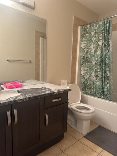 a bathroom with a toilet and a shower curtain at Cozy Vibe 2 bedroom Apartment in Edmonton