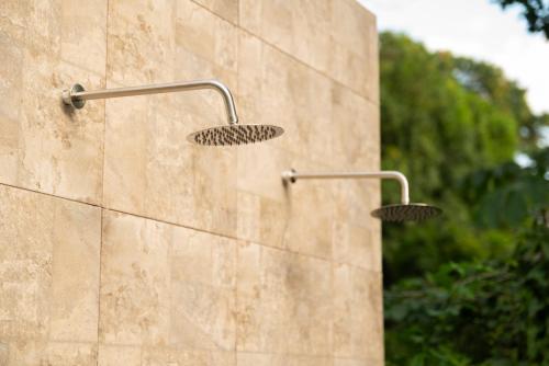 two shower heads on the side of a stone wall at Amalfi Surf Lodge in ChiltiupÃ¡n