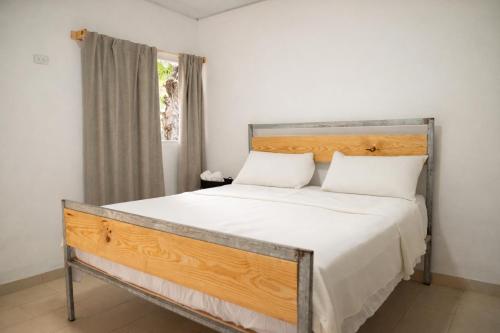 a bedroom with a large bed with white sheets and a window at Amalfi Surf Lodge in ChiltiupÃ¡n