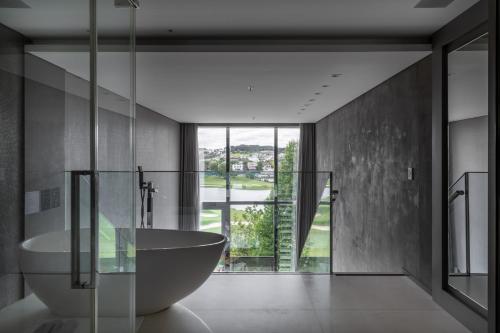 a bathroom with a tub and a large window at Suryaa Hotel Pinhais, Curio Collection by Hilton in Pinhais