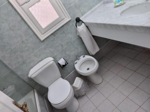 a bathroom with a white toilet and a sink at Solanas Termas de Dayman in Termas del Daymán