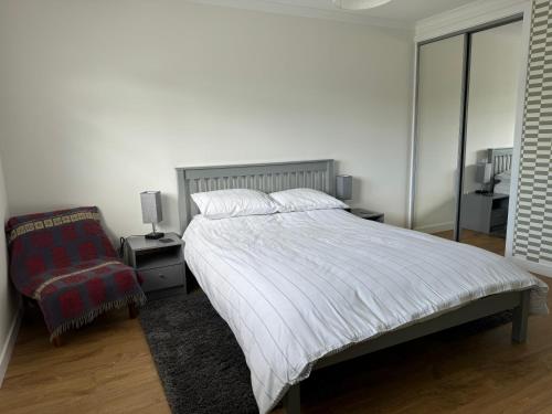 a white bedroom with a bed and a chair at Leagarth House in Baltasound