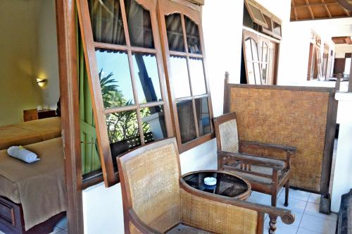 a room with chairs and a table and windows at Yulia 2 Homestay Sanur in Sanur