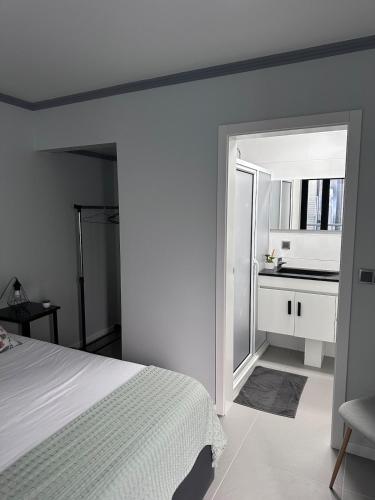 a bedroom with a white bed and a kitchen at Harmonia Guest House in Ponta Delgada