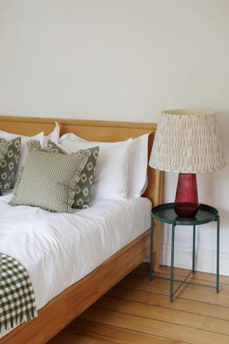 a bed with a red lamp on a table at Stylish, Spacious, Oxford Townhouse, Driveway parking in Oxford