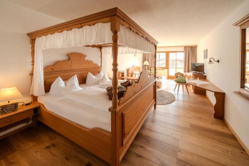 a bedroom with a large wooden bed with a canopy at Wohlfühlhotel zur Post in Langdorf