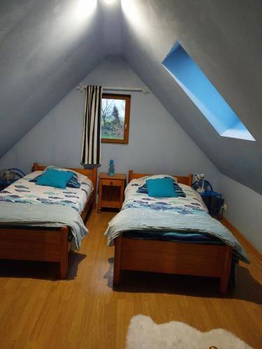 a attic bedroom with two beds and a window at Gîte - La campagne in Sainte-Hélène-Bondeville