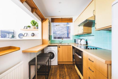 a small kitchen with a washer and dryer at Beautiful one bed garden flat in Muswell hill in London
